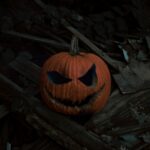 a carved pumpkin on a log