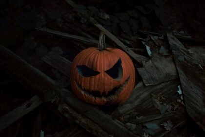 a carved pumpkin on a log